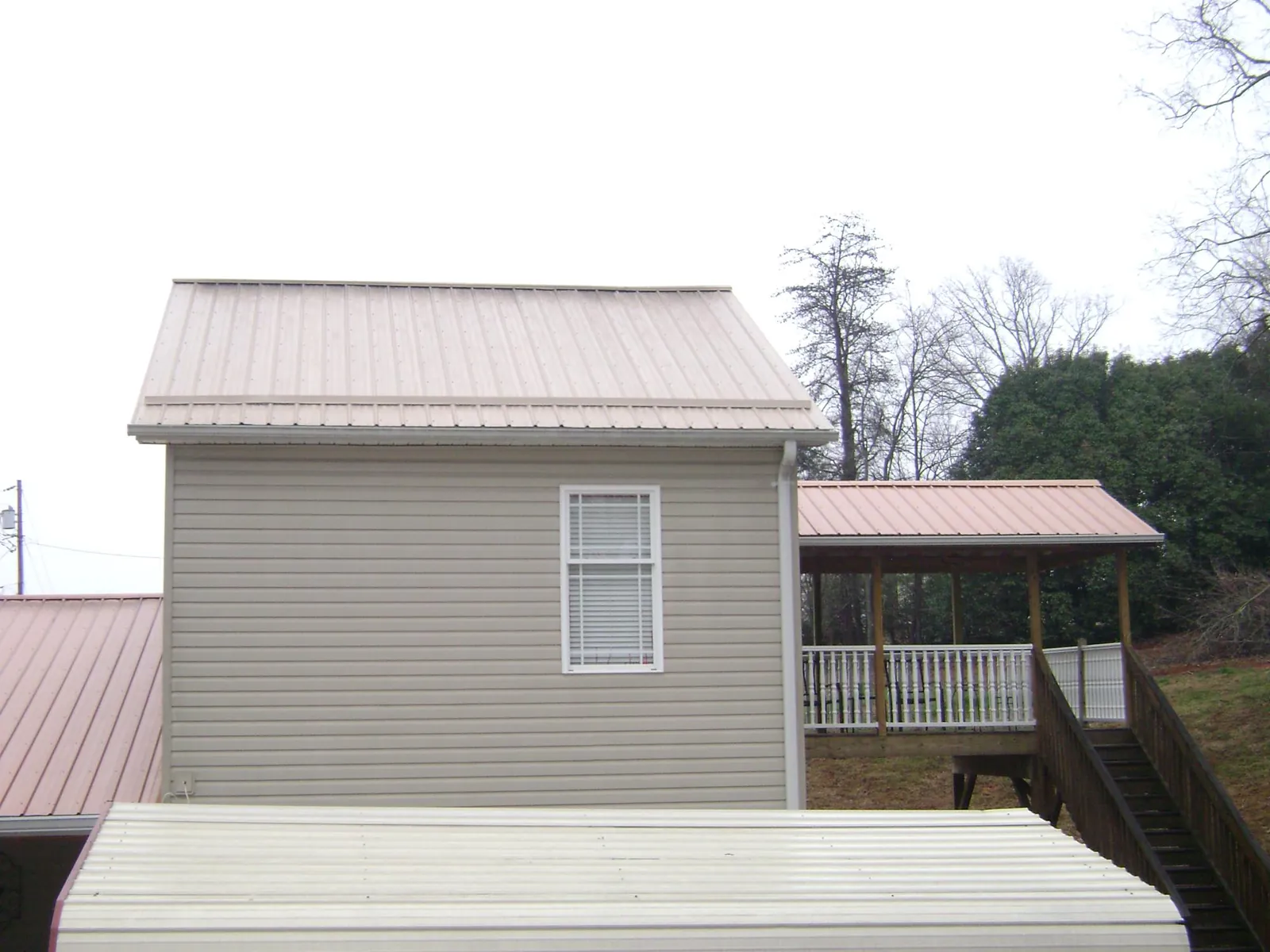 Tan metal roofs on a two story addition and attached porch, from a Roof Replacement job in Port Royal