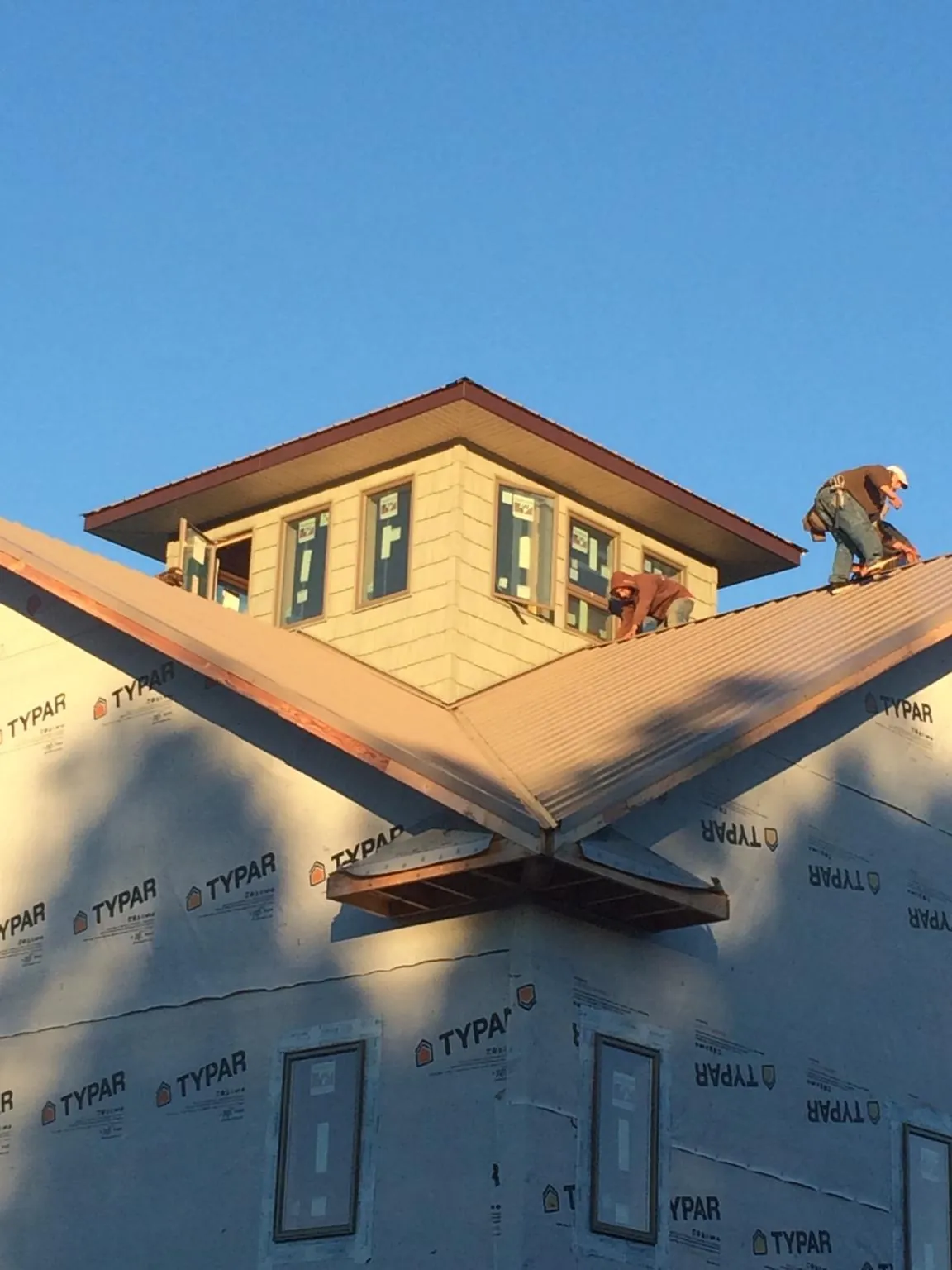 Roofers working around a rooftop cupola on a new metal roof at sunset — Roof Waterproofing in Port Royal by Roofing Brothers